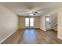 Spacious living room featuring wood-look floors, a ceiling fan, and abundant natural light through the windows at 955 Laurel Mill Dr, Roswell, GA 30076