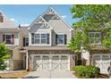 Well-maintained townhouse featuring a two-car garage, brick accents, and landscaped front at 2894 Cross Creek Dr, Cumming, GA 30040