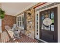 Inviting front porch with brick flooring, stone walls, rocking chairs, and a charming welcome sign on the front door at 403 Grassmeade Way, Snellville, GA 30078