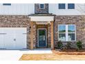 Inviting front entry featuring a modern door with glass panes, brick columns, and stylish lighting at 4202 Adler Cir, Buford, GA 30519