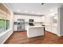 Bright kitchen features white cabinets, stainless steel appliances, granite countertops and a center island on dark hardwood floors at 11302 Musette Cir, Alpharetta, GA 30009