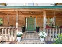 Inviting front porch with wood flooring, green door, and decorative flower planters at 135 Fiddle Crk, Social Circle, GA 30025