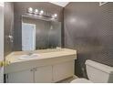 Small bathroom with wallpaper, big mirror, vanity, and commode at 3312 Northcrest Rd # C, Atlanta, GA 30340