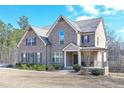 Inviting two-story home featuring a brick facade, covered porch, and a lush front yard at 7751 Capps Ridge Ln, Douglasville, GA 30135