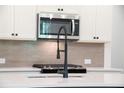 The kitchen features white cabinets, stainless steel microwave, and modern faucet at 1616 Ruskin Way, Marietta, GA 30062