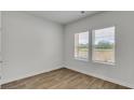 Well-lit bedroom featuring wood-look floors and two windows with natural light at 668 Egrets Landing #64, Covington, GA 30014