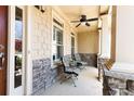 Inviting front porch with stone accents, comfortable seating, and a ceiling fan for relaxing outdoors at 5095 Hamby Hollow Ln, Cumming, GA 30028