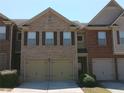 Townhome exterior with brick facade, two-car garage, and neatly manicured bushes at 2162 Oakland Grove Pl, Lawrenceville, GA 30044