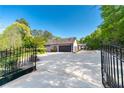Long driveway leading to a detached garage, complemented by wrought iron gates and lush greenery at 2320 Copper Trail Ln, Buford, GA 30519