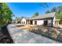 Side view of a one-story home, showcasing the spacious driveway, manicured lawn, and classic architectural style at 2320 Copper Trail Ln, Buford, GA 30519