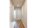 Hallway with wood flooring, white trim, and a glimpse into an adjacent bathroom at 7505 Woolf Way, Cumming, GA 30028