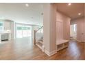Bright, open-concept living space with wood floors, staircase, and built-in storage at 7505 Woolf Way, Cumming, GA 30028