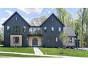 Striking modern farmhouse with dark vertical siding, complemented by light wood accents and an arched front door at 115 Nova Ln, Roswell, GA 30075