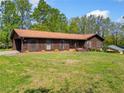 Ranch-style house on expansive lawn featuring mature trees and side carport at 4927 Bedell Ne Rd, Roswell, GA 30075