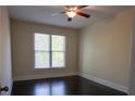 A cozy bedroom features a ceiling fan and a bright window, complemented by neutral walls and dark hardwood flooring at 610 Big Bend Trl, Sugar Hill, GA 30518