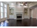 Bright living room boasts a fireplace with custom shelving, large windows, dark hardwood floors, and a ceiling fan at 610 Big Bend Trl, Sugar Hill, GA 30518