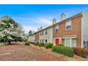 Exterior view of the townhome row, with neat landscaping, red doors, and blooming tree at 992 Old Holcomb Bridge Rd, Roswell, GA 30076