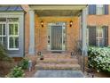 Elegant front door with sidelights and brick steps flanked by manicured bushes and lighting at 1151 Goodwin Ne Rd, Brookhaven, GA 30324