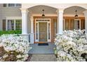 Inviting front porch with classic columns, decorative brickwork, and blooming white azalea bushes at 5177 Cabot Creek Dr, Buford, GA 30518