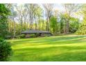 Expansive green lawn leading to a cozy home surrounded by mature trees creating a serene and private setting at 1850 Winchester Trl, Brookhaven, GA 30341