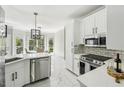 Modern kitchen with white cabinets, quartz counters, stainless steel appliances, and a view of the dining area at 1961 Flowering Dr, Grayson, GA 30017