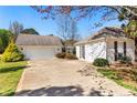 Exterior showing the home's white siding, driveway, and a detached garage on a sunny day at 65 Woodside Ct, Mcdonough, GA 30253