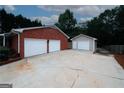 View of detached two-car garage with extra storage and a large cracked concrete driveway at 2533 Whispering Pines Dr, Grayson, GA 30017