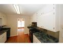 Galley kitchen with white cabinets, dark countertops and hardwood floors at 2533 Whispering Pines Dr, Grayson, GA 30017