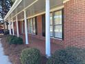 Inviting covered porch with white columns, adding charm to the red brick home exterior at 2533 Whispering Pines Dr, Grayson, GA 30017