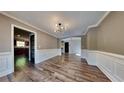 Formal dining room featuring elegant wainscoting, hardwood floors, and a modern chandelier at 609 Millstone Dr, Jonesboro, GA 30238