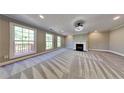 Spacious living room with a cozy fireplace, plush carpeting, and large windows for natural light at 609 Millstone Dr, Jonesboro, GA 30238