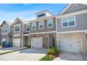 View of townhome exteriors with stone accents, garages, and well-maintained landscaping at 6415 Shalks Crossing Dr, Lithonia, GA 30058