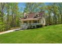 Charming cottage-style home with front porch, dormer windows, and a lush lawn surrounded by mature trees at 388 Pine Trl, Canton, GA 30115