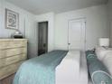 Bright bedroom features a neatly made bed with a teal blanket, neutral walls, and a wooden dresser at 3333 Tarian Way, Decatur, GA 30034