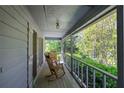 Inviting outdoor covered porch with wood flooring, railing, and a view of trees at 5534 Blackhawk Dr, Acworth, GA 30102