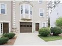 Exterior of a tan townhome with one car garage, bay window, and manicured landscaping at 988 Vintage Pointe Dr, Lawrenceville, GA 30044
