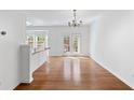 Open-concept dining room featuring hardwood floors, a stylish chandelier, and access to the outdoor deck through french doors at 3972 Church View Ln, Suwanee, GA 30024