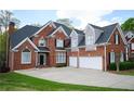 Brick home showing garage doors, a paved driveway, professional roof, and well-maintained lawn at 2165 Sugarstone Ct, Lawrenceville, GA 30043