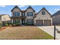 Elegant two-story home featuring a well-manicured lawn, a two-car garage, and a classic brick facade at 4585 Woodland Bank Blvd, Buford, GA 30518