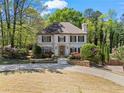 Beautifully landscaped home with a circular driveway and lush greenery surrounding the property at 9860 Hunt Club Way, Johns Creek, GA 30022