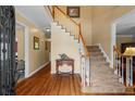 Open foyer featuring hardwood flooring and a staircase with carpeted treads at 9860 Hunt Club Way, Johns Creek, GA 30022