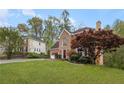 Charming two-story brick home with an attached two-car garage, mature trees, and a well-manicured lawn at 3025 Kaley Nw Dr, Kennesaw, GA 30152