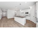 Bright kitchen with a granite island, white cabinets, stainless steel appliances, and modern lighting at 358 Orwell Dr, Social Circle, GA 30025