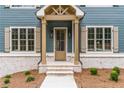 Inviting front entrance featuring a wooden door, brick accents, and decorative shutters at 7636 Chestnut Hill Rd, Cumming, GA 30041