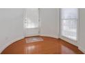 Sunlit entry way with hardwood floors, white door, and windows with blinds at 12554 Huntington Trce, Alpharetta, GA 30005