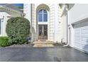 Grand entrance of a white home, featuring arched windows, stone steps and double doors at 7080 Greatwood Trl, Alpharetta, GA 30005