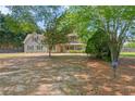 Two-story home with light-blue siding, red shutters, and a sprawling front yard with mature trees at 4531 Cedar Dr, Loganville, GA 30052