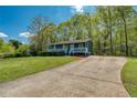 Inviting one-story home with a lovely front porch, surrounded by a lush green lawn and mature trees, plus long driveway at 166 Rustin Dr, Dallas, GA 30157