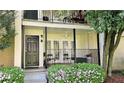 Close-up of condo balcony with black railing, seating, neutral decor, and garden bed full of bright flowers at 311 Peachtree Hills Ne Ave # 17C, Atlanta, GA 30305