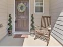 Inviting front porch with rocking chair and spiral topiaries at 706 Woodland Pl, Woodstock, GA 30188